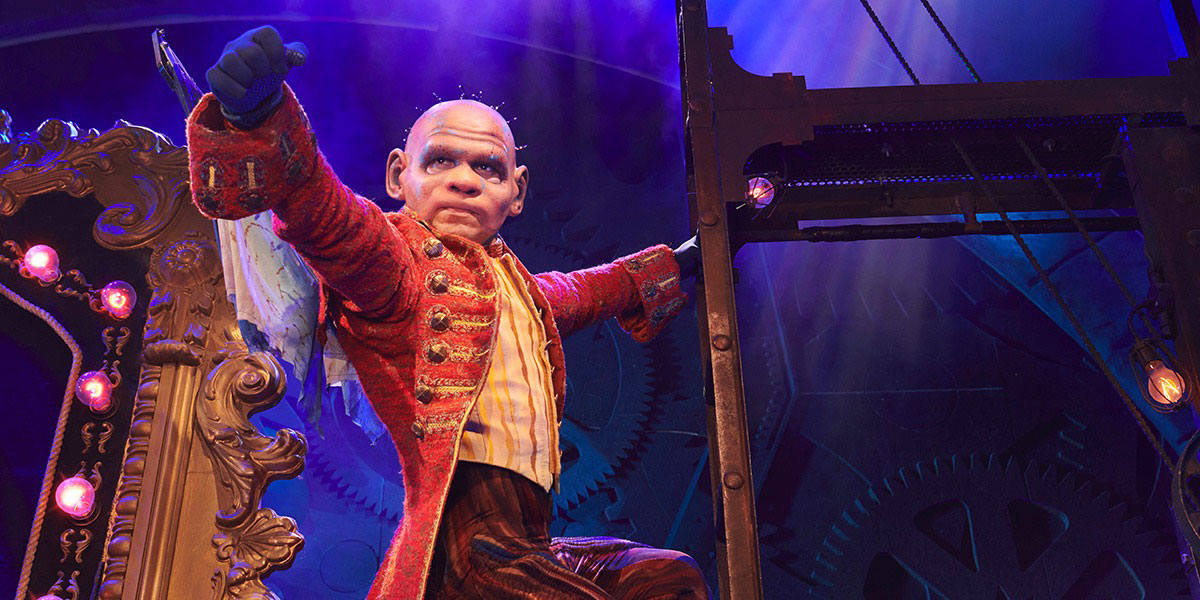 Iroy Abesamis performing on stage in a green costume, with dramatic lighting and a dark background.