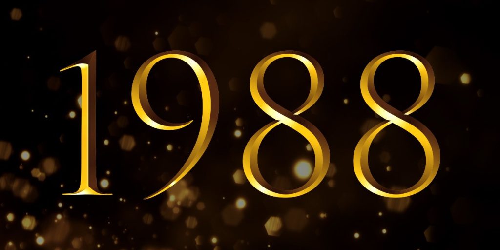 A group of elegantly dressed individuals stands on stage, holding awards, with a spotlight illuminating them.