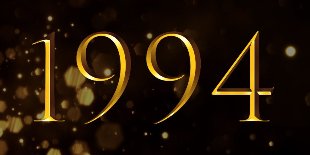 Golden numbers "1994" on a dark background with subtle bokeh effects, suggesting a celebratory theme.