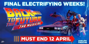 A scene from Back To The Future The Musical featuring characters in vibrant costumes, with a dynamic stage backdrop.