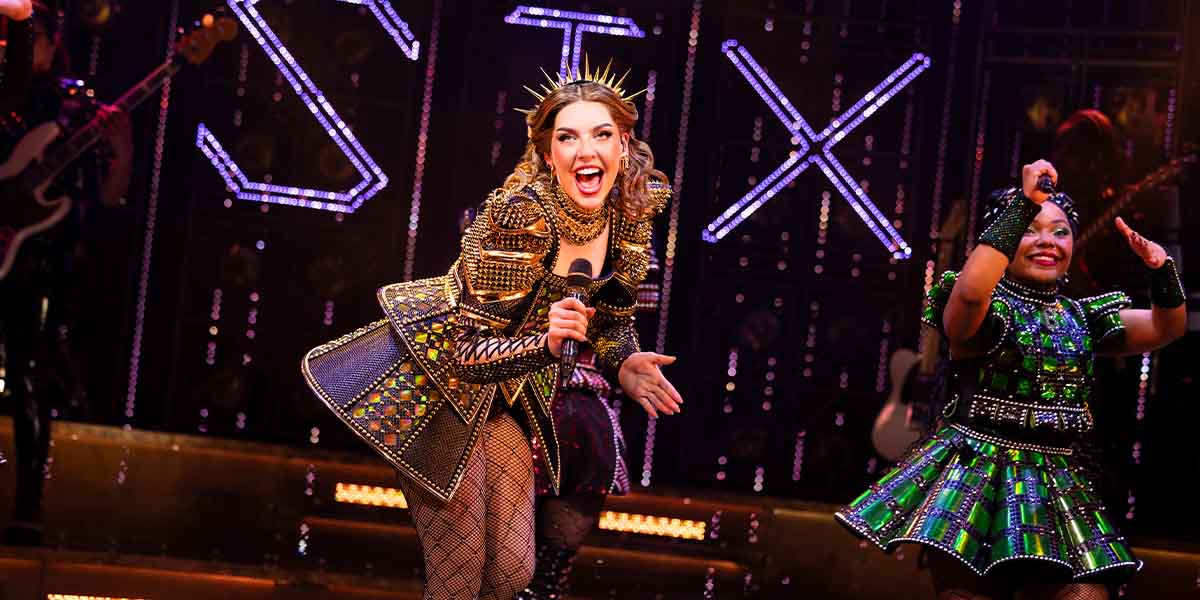 Adrianne Langley as Catherine of Aragon performs energetically, while Marisha Morgan as Anne Boleyn smiles.