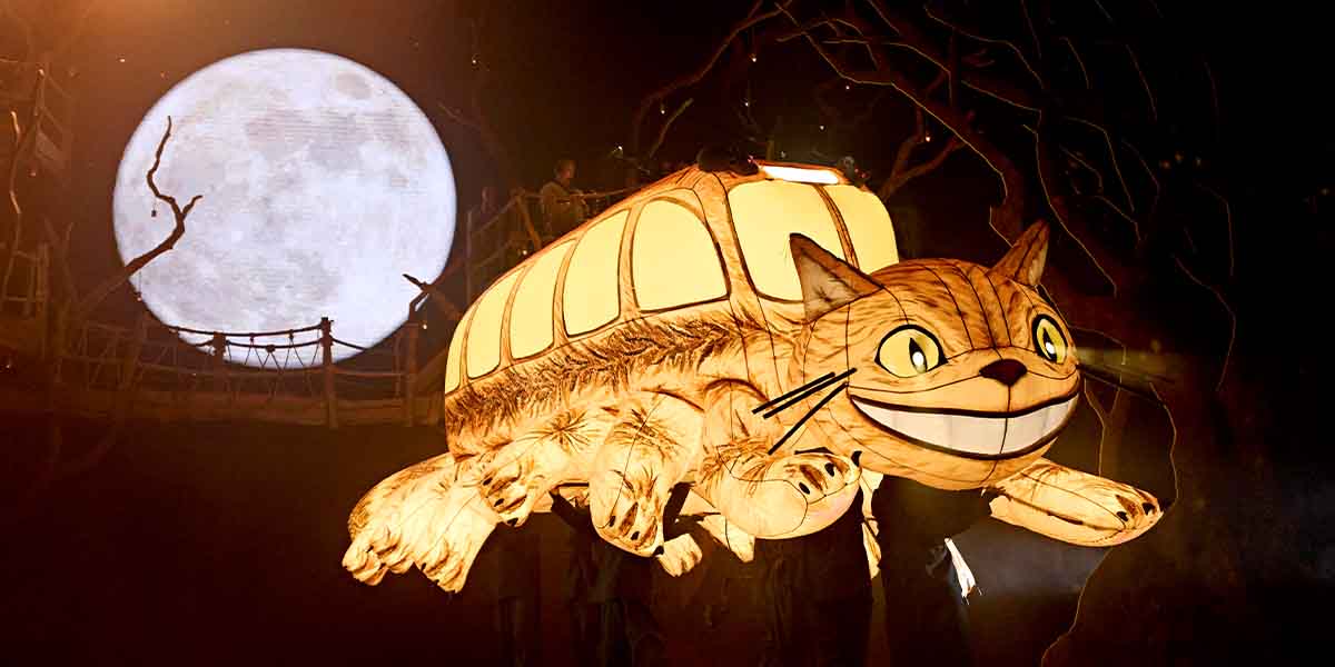 A large, illuminated cat-like creature floats against a full moon backdrop, surrounded by dark trees.