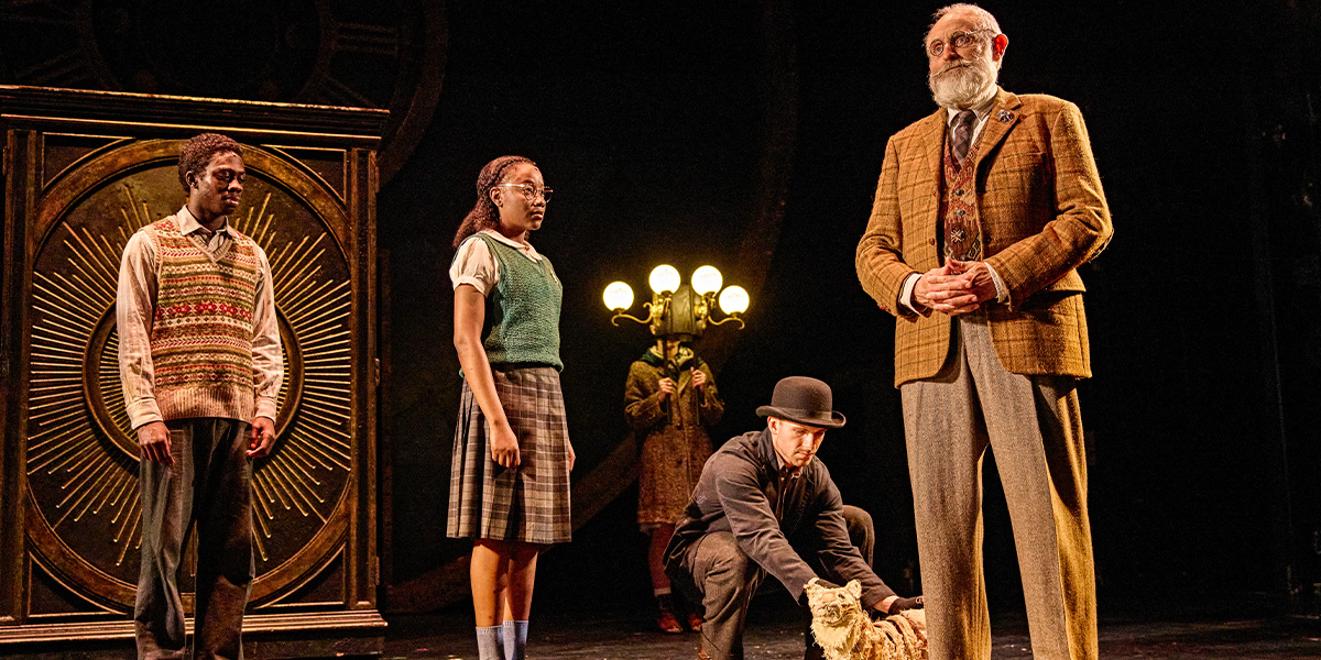 Three people are standing on stage with a cat.