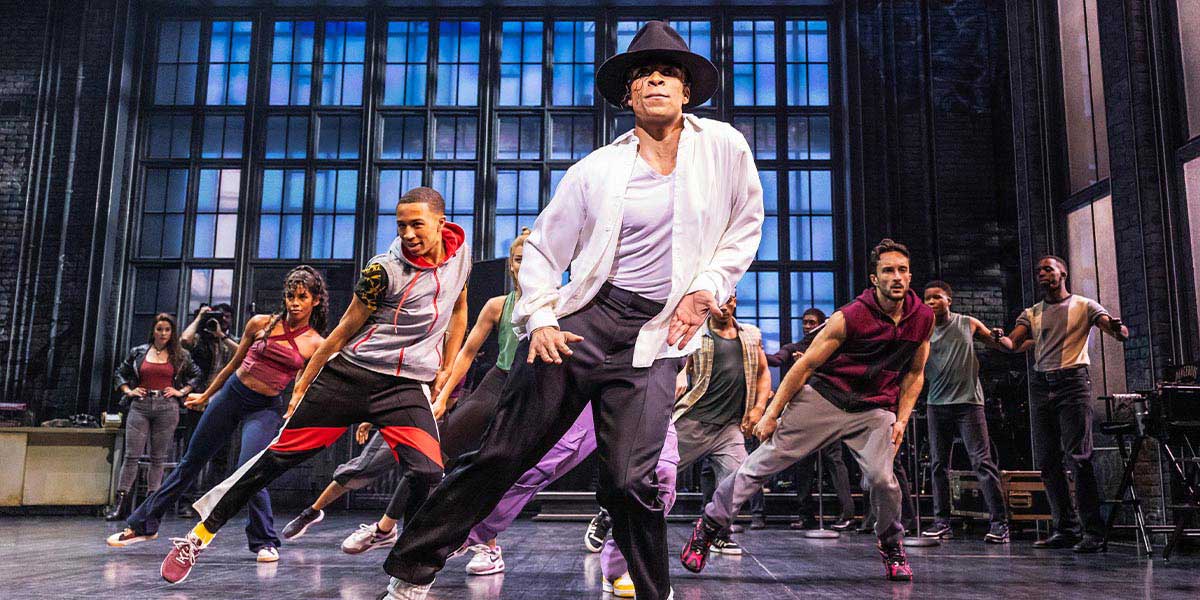 A vibrant stage scene from "MJ The Musical," featuring dancers in dynamic poses and colourful costumes.