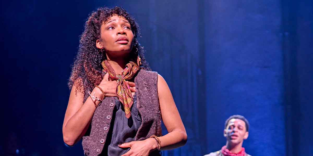 Bethany Antonia performs expressively, wearing a scarf and vest, with Marley Fenton visible in the background.
