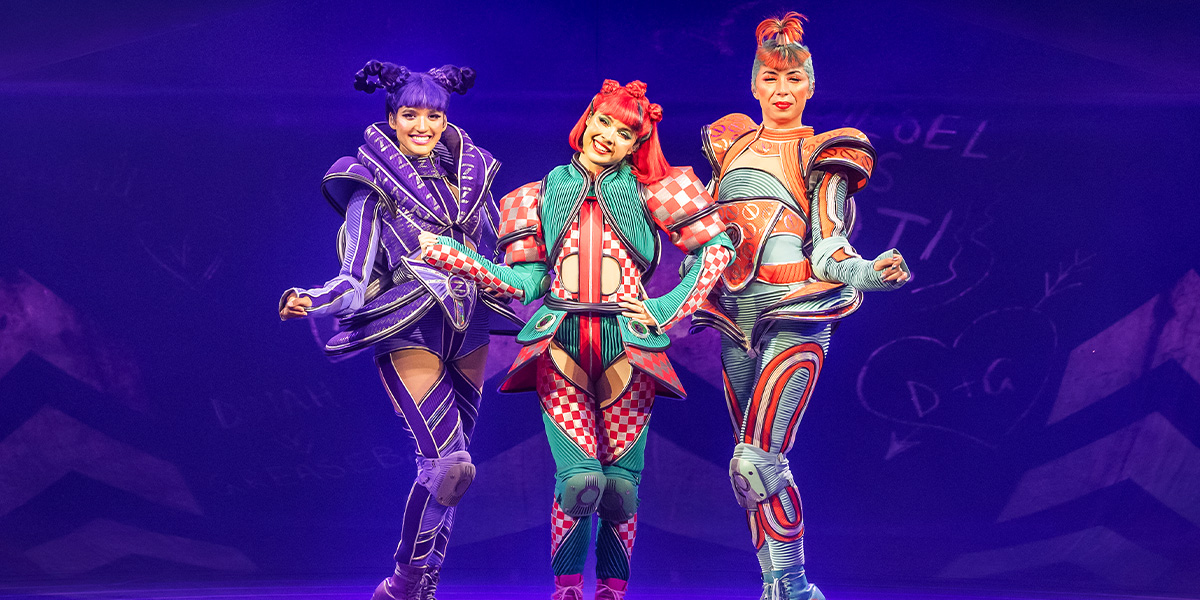 A vibrant stage scene with performers in colourful costumes, showcasing dynamic poses and dramatic lighting effects.