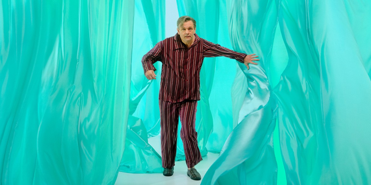 A man in his pyjamas wading through blue fabric.