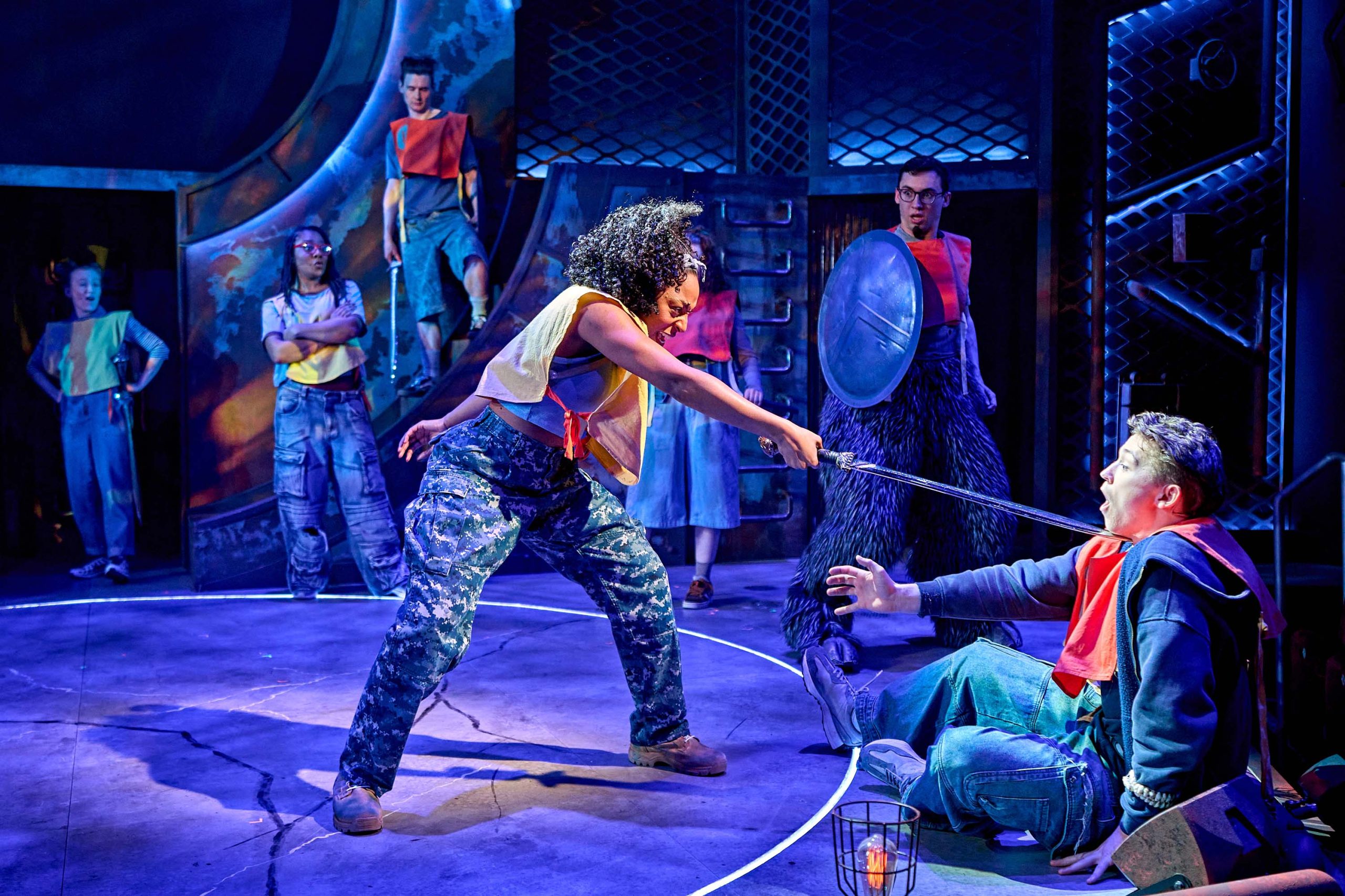 A character is standing on stage holding a sword to the throat of another.