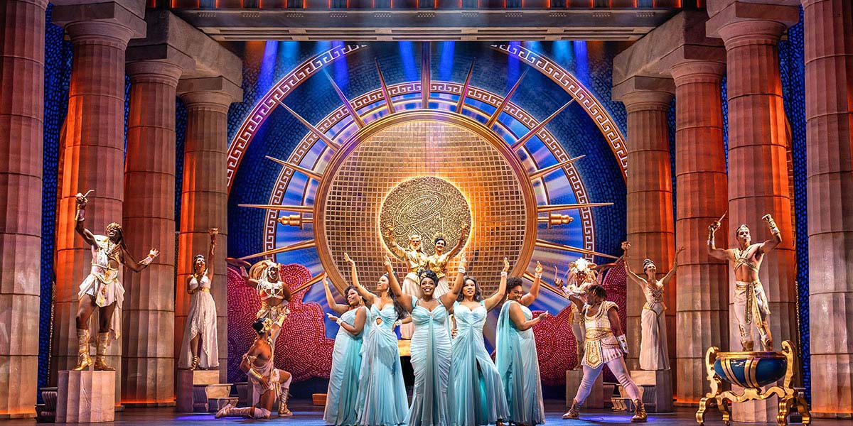 The Muses from Disney's Hercules pose together on Mount Olympus, showcasing vibrant costumes and expressive gestures.