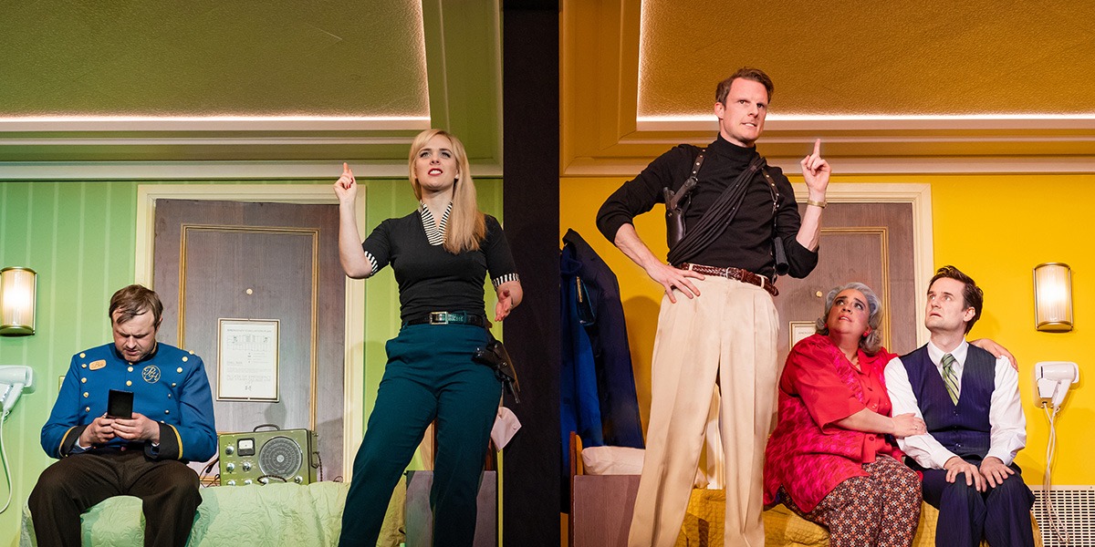 Two people are standing central holding 1 finger up as if to indicate they have had an idea.