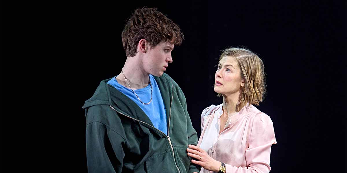 Cormac McAlinden and Rosamund Pike share an intense moment on stage, dressed in casual attire.