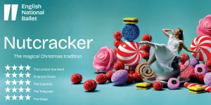 A wooden nutcracker figure in a red and gold uniform stands against a blurred festive background.