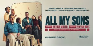 A modern mirror with a sleek frame reflects a bright, minimalist room with neutral tones.