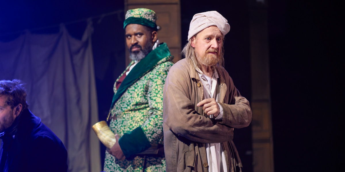 Two actors perform in a scene from A Christmas Carol, wearing period costumes with dramatic expressions.