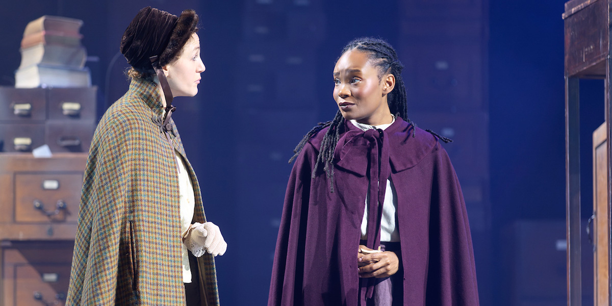 A scene from A Christmas Carol featuring actors in Victorian costumes, with festive decorations in the background.