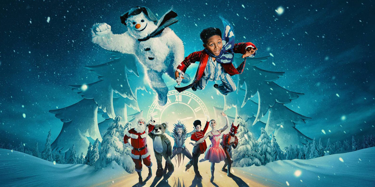 A snowman with a black hat and scarf stands on stage, surrounded by festive decorations and soft lighting.