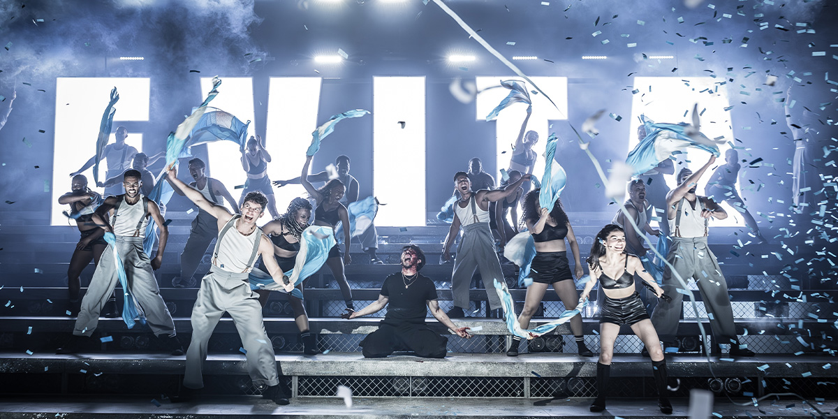 A group of performers on stage with dynamic lighting and confetti effects.