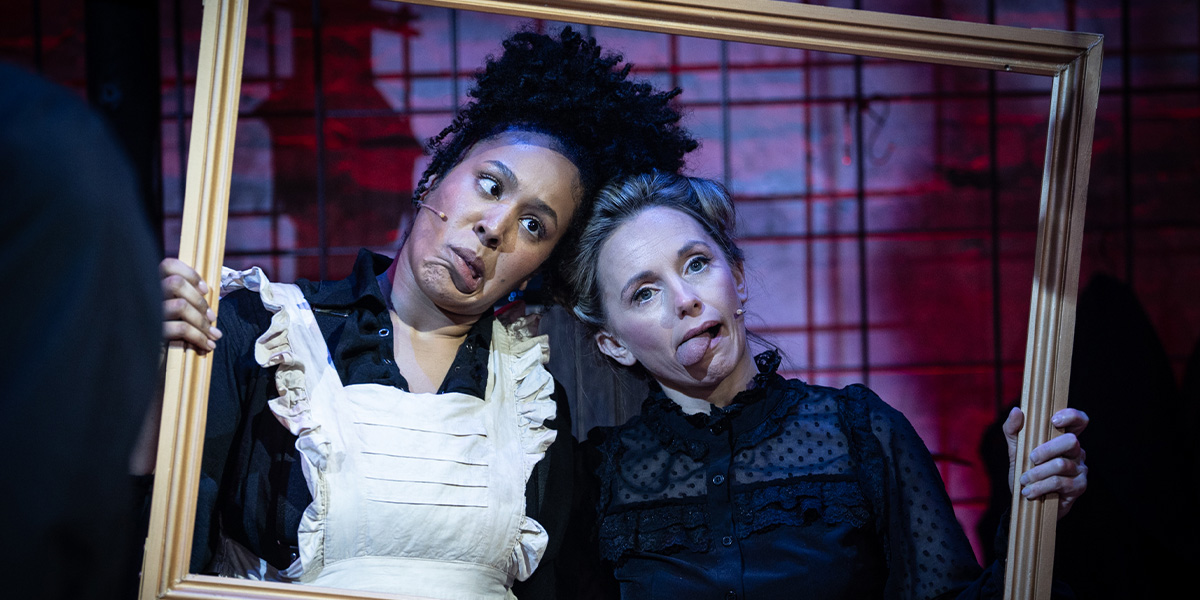 Two people hold up a large gold photo frame and pose inside it pulling silly facial expressions.