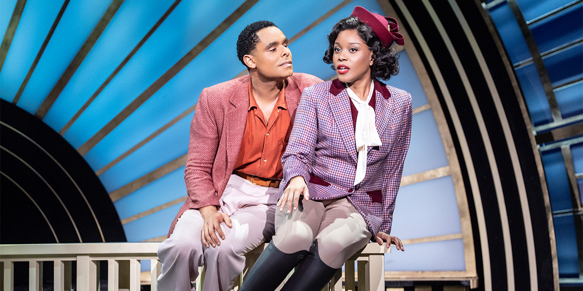 Two people in formal attire sit together on a bench.