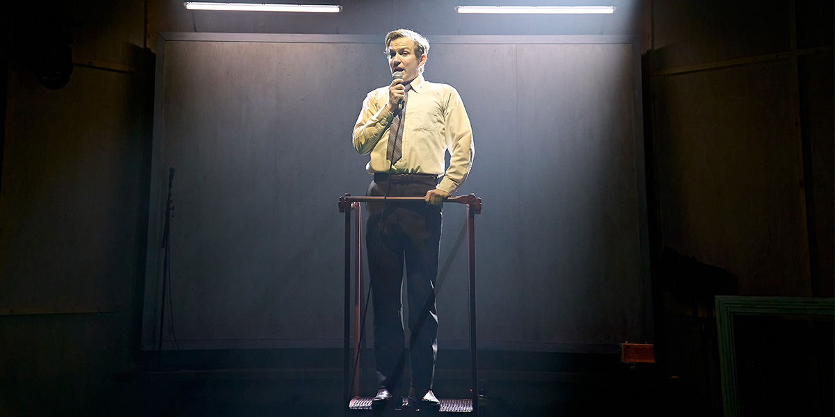 Jack Holden stands confidently in a stylish outfit, surrounded by a vibrant, modern set design.