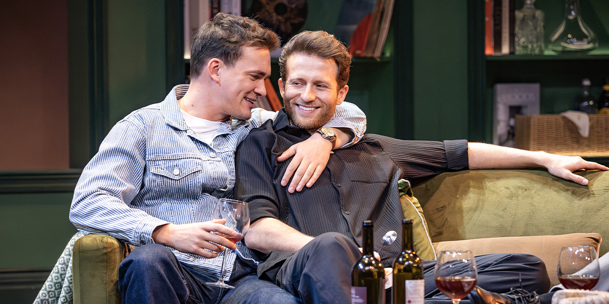 Two people sit cuddled up on a sofa.