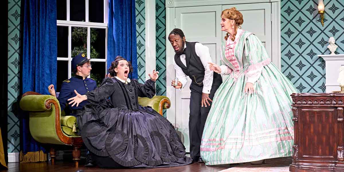 Four actors in period costumes perform in a brightly lit room with green wallpaper and a sofa.