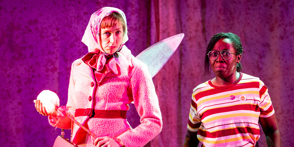 A dancer in a pink tutu performs an arabesque on stage, with a festive backdrop and soft lighting.