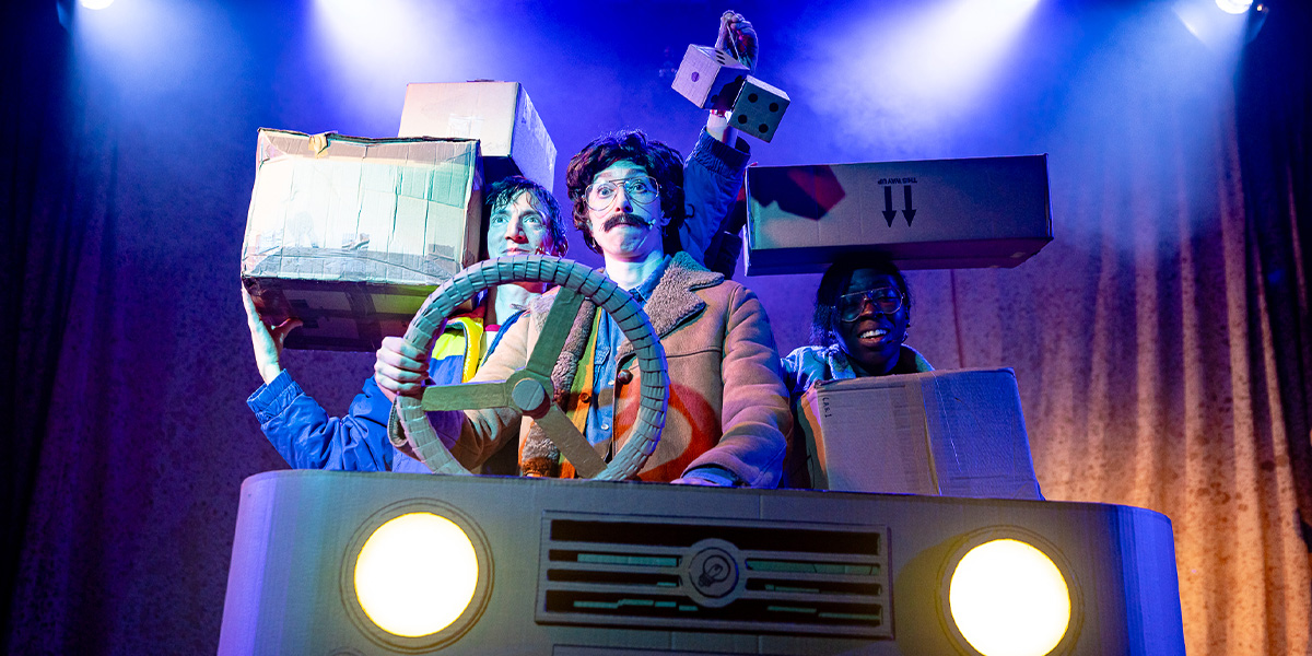 A ballet dancer in a white tutu performs an arabesque, set against a festive, decorated stage backdrop.