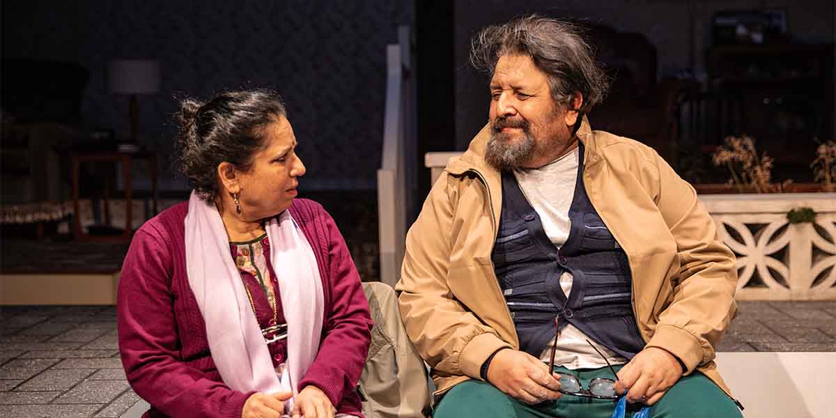 Shobu Kapoor as Hema and Rehan Sheikh as Liaquat sit together, engaged in conversation on stage.