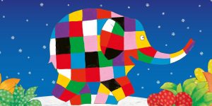 A colourful patchwork elephant stands against a blue background with snowflakes, surrounded by green foliage and fruit.