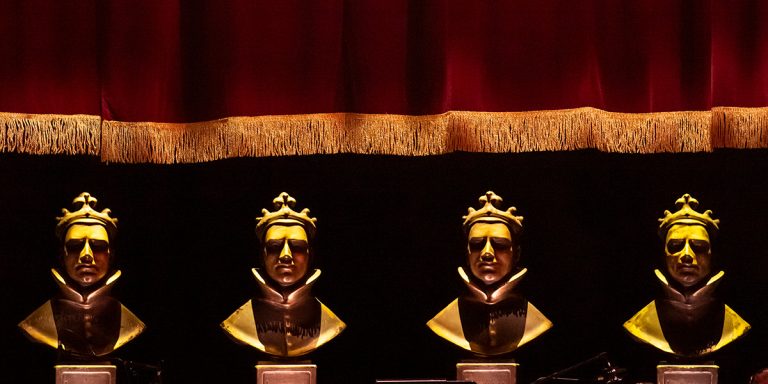 A bronze statue of Larry stands on a pedestal, surrounded by flowers and candles in remembrance.