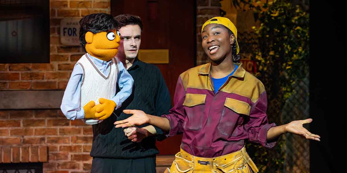 Noah Harrison holds a puppet while Dionne Ward-Anderson gestures expressively, both on a vibrant stage.