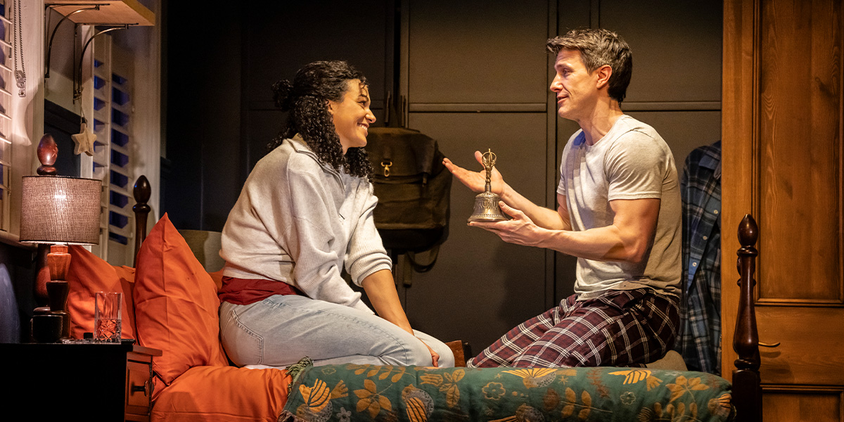 two people stand in a dimly lit room, holding a flashlight, with shadows cast on the walls.