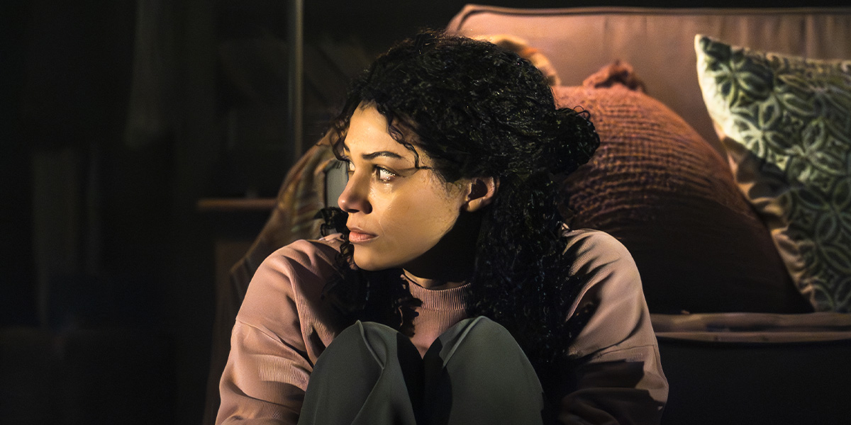 a person stands in a dimly lit room, looking intently at a flickering light source.