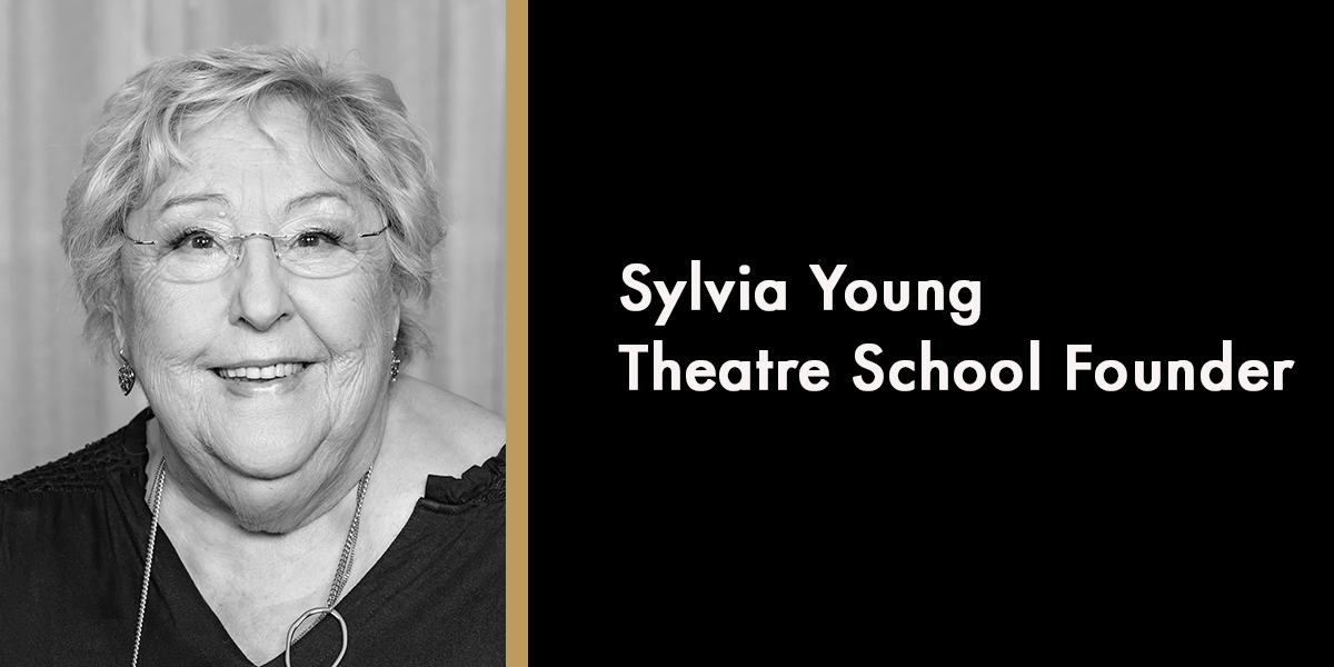 A young woman named Sylvia, smiling, with long dark hair, wearing a floral dress against a soft background.