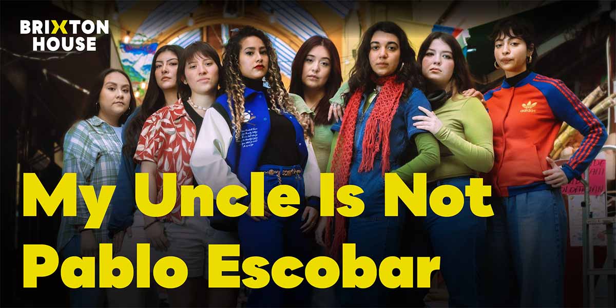 A man with dark hair and a beard stands in front of a colourful mural depicting Pablo Escobar.