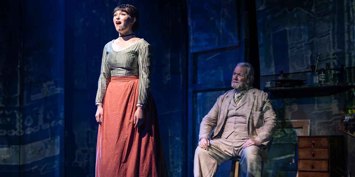 Brooke Bazarian sings passionately while Jeff Shankley listens intently, set against a dramatic backdrop.