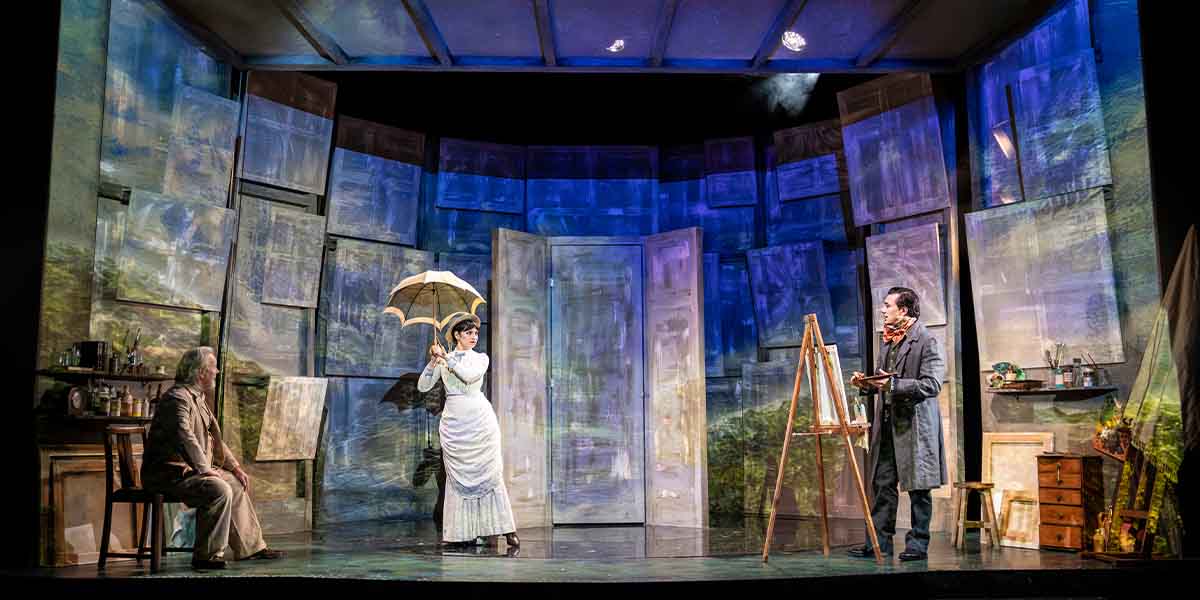 Jeff Shankley, Brooke Bazarian, and Dean John-Wilson perform on stage with painted backdrops and props.