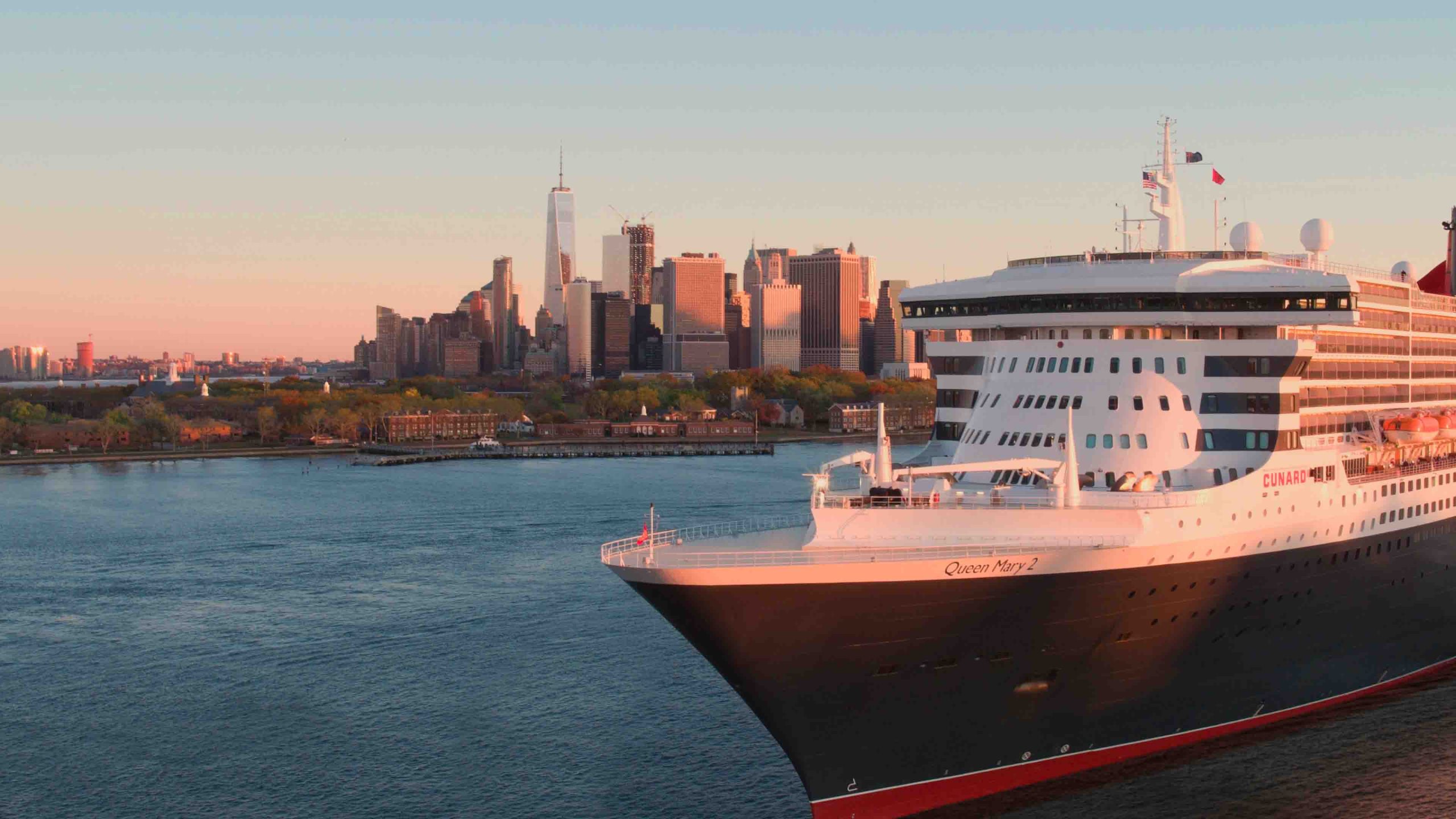 A group of elegantly dressed individuals at a gala event, with a red carpet and decorative lighting.