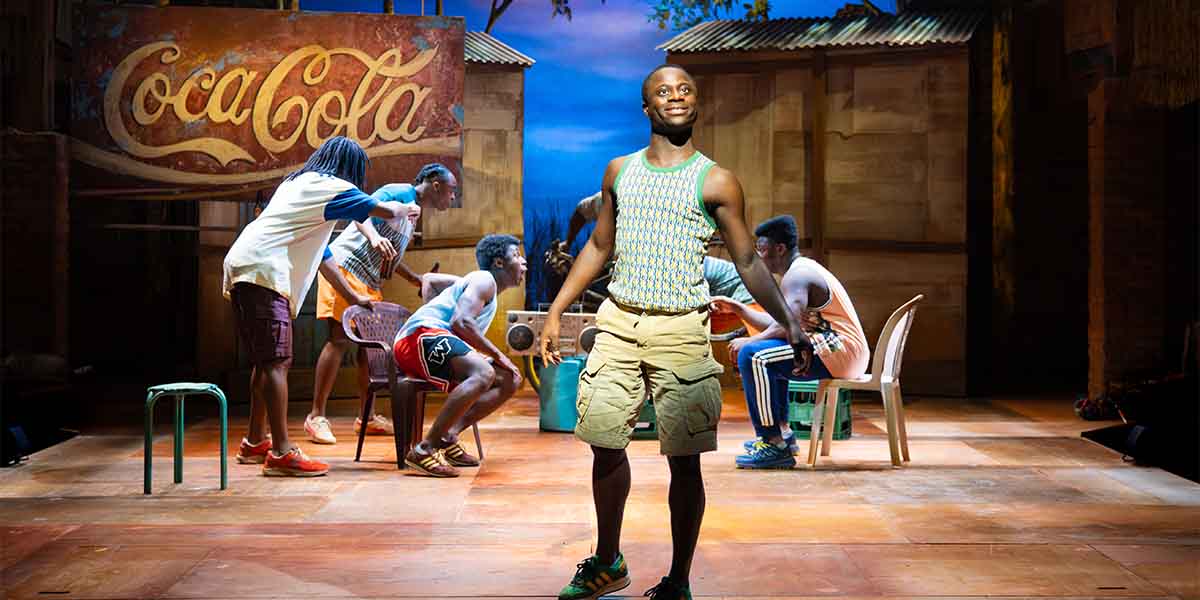 A young person in a striped tank top stands confidently, surrounded by seated performers in casual attire.