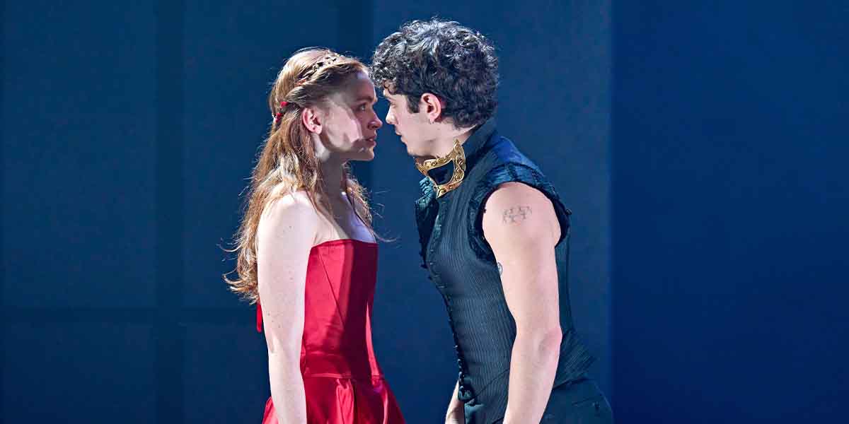 Sadie Sink and Noah Jupe face each other intensely, dressed in a red dress and black attire.