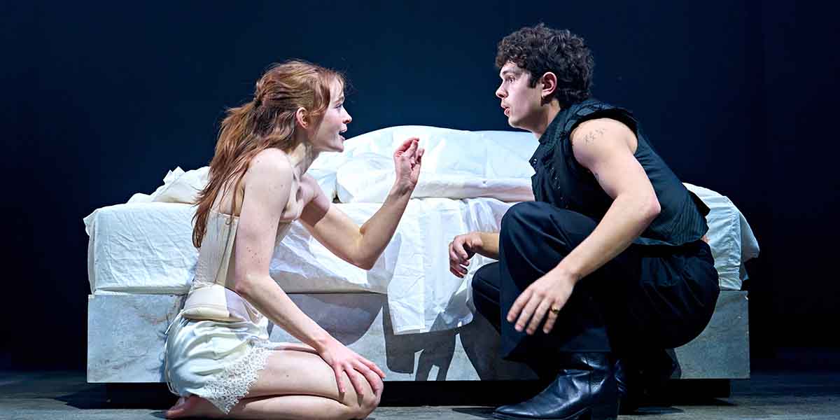 Sadie Sink and Noah Jupe in a dramatic scene, seated on a bed, engaged in intense conversation.