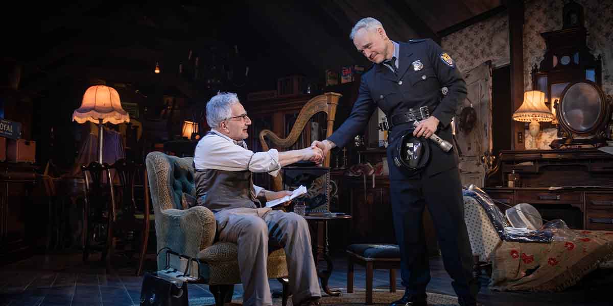 Two people shake hands in a dimly lit room filled with vintage furniture and decor.