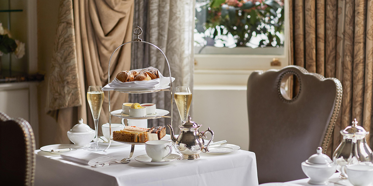 Elegant afternoon tea setup at Egerton House Hotel, featuring fine china, pastries, and a floral arrangement.