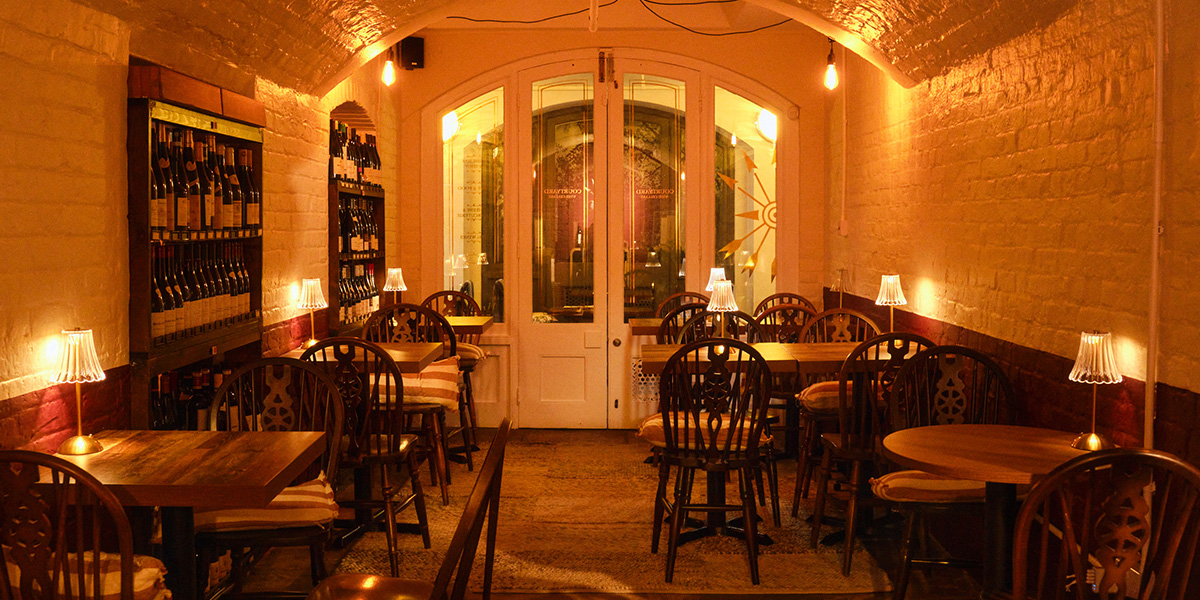 A beautifully arranged wine cellar with wooden shelves filled with bottles, soft lighting, and a rustic stone wall.