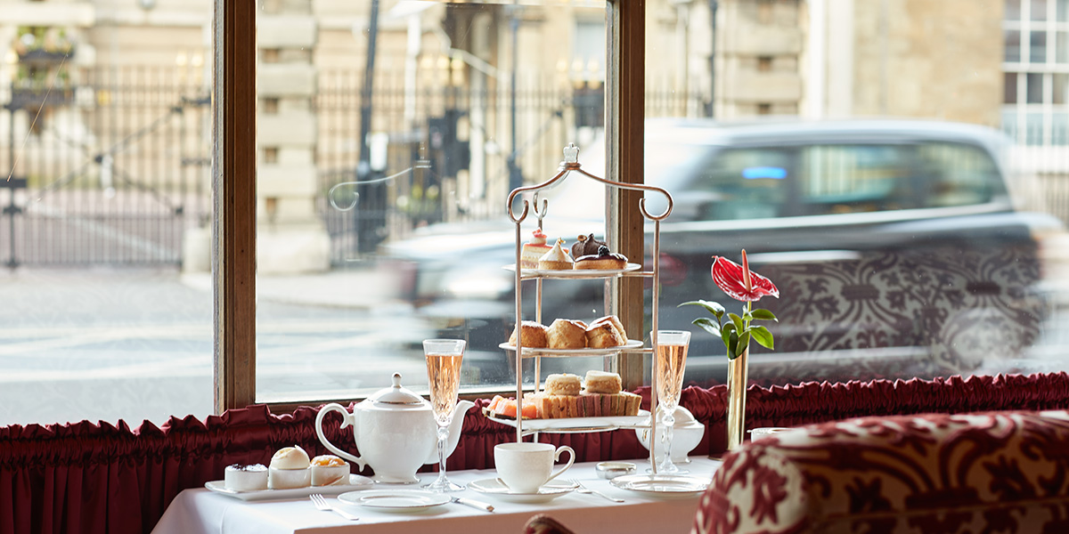 A beautifully set table with elegant tea service, surrounded by guests enjoying afternoon tea at The Rubens.