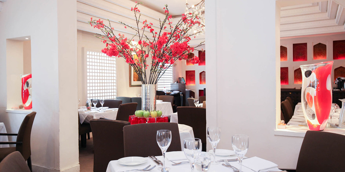 A vibrant interior of Salloos Restaurant featuring wooden tables, colourful decor, and patrons enjoying their meals.