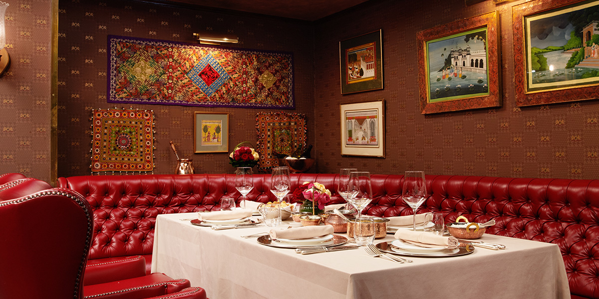 A vibrant curry dish garnished with herbs, served in an elegant restaurant setting with soft lighting.