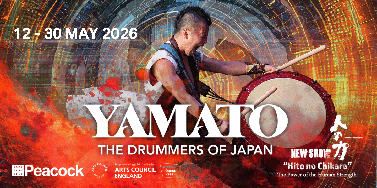 A group of drummers in traditional attire performing energetically on stage, with vibrant drums and dynamic movements.