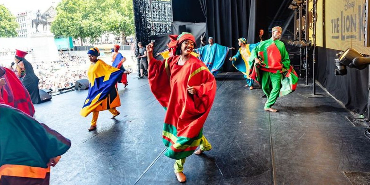 A vibrant stage performance of Disney's The Lion King, featuring actors in elaborate costumes and dynamic poses.